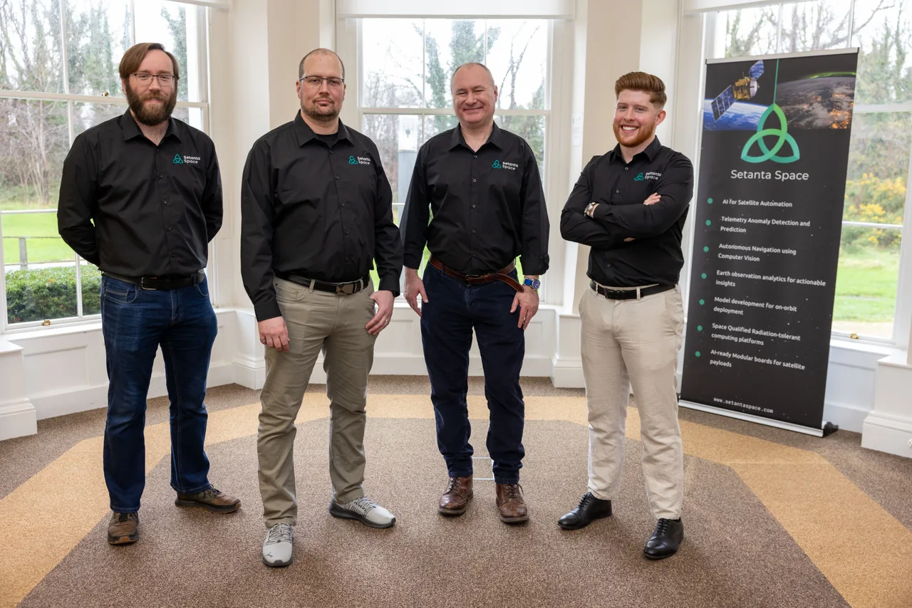 Four members of the Setanta Space team together beside the company banner